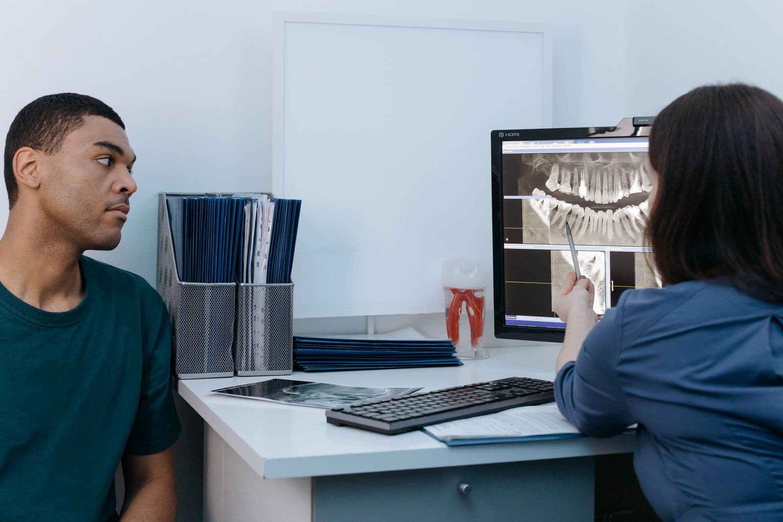 Dental consultation with an X-ray displayed on a screen