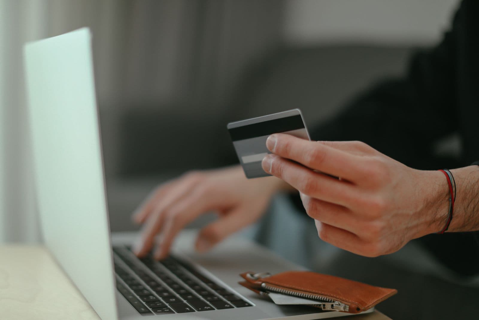Hands holding a payment card beside a laptop