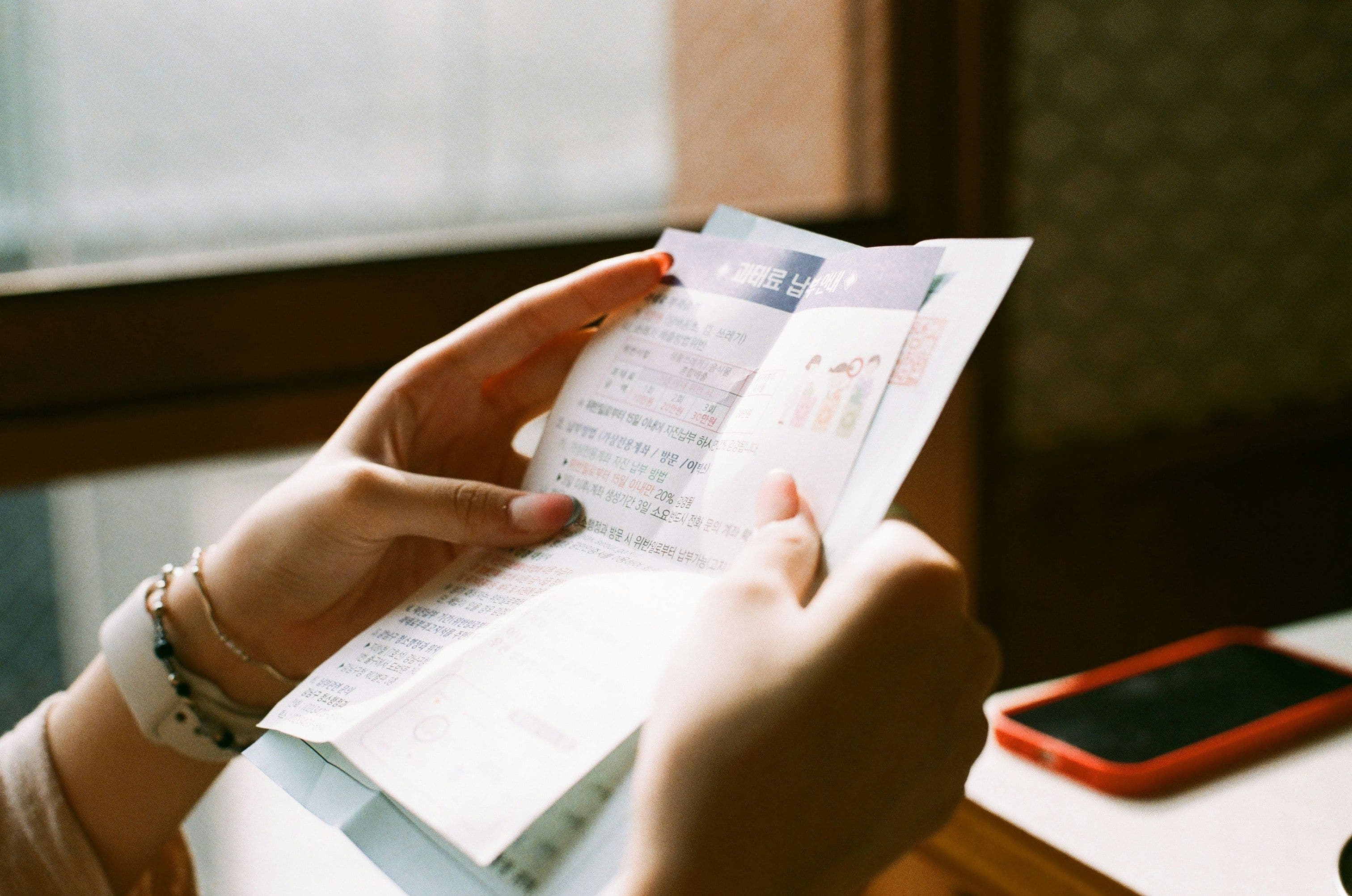 Hands reviewing a household utility bill beside a phone on a table