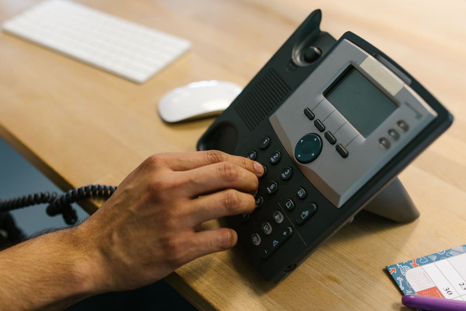 A person dialling a desk telephone