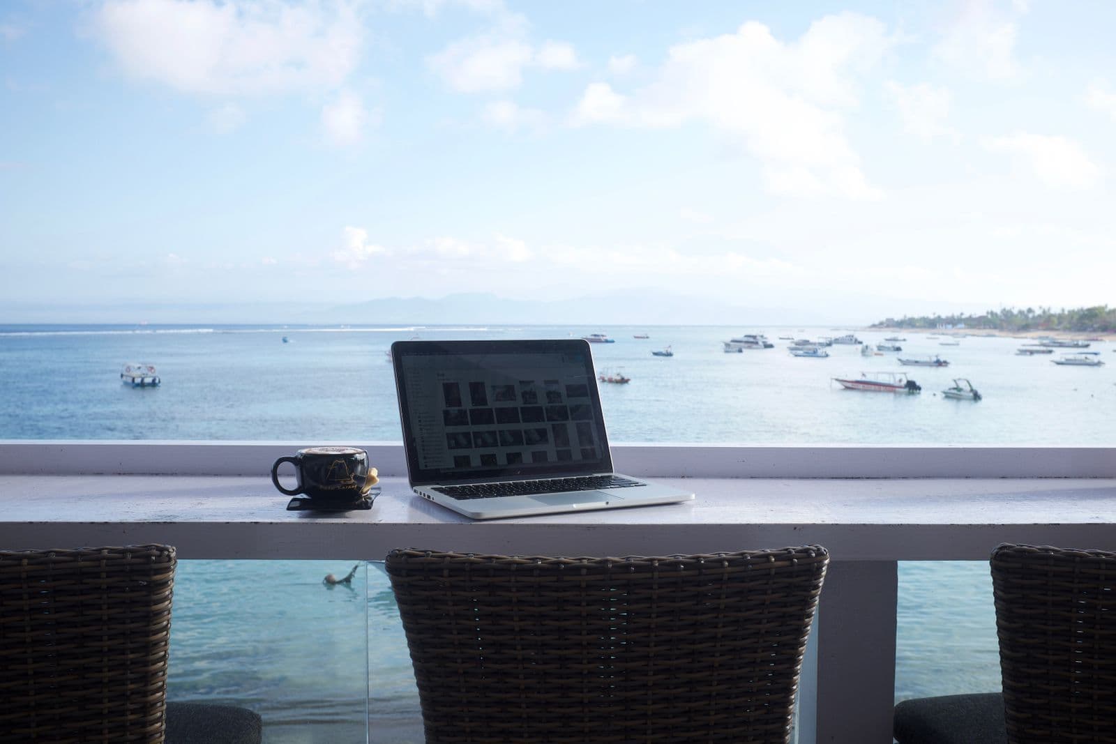 Laptop on a table beside windows overlooking the sea