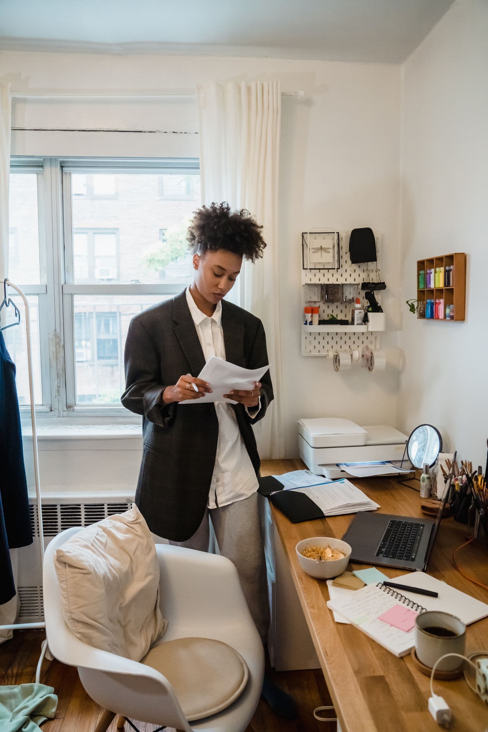 Woman checking documents beside a laptop at home