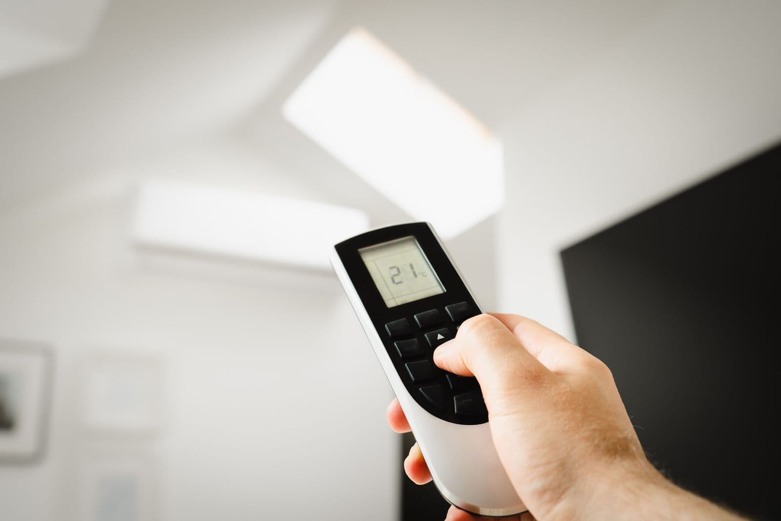 Hand holding an air-conditioning remote indoors
