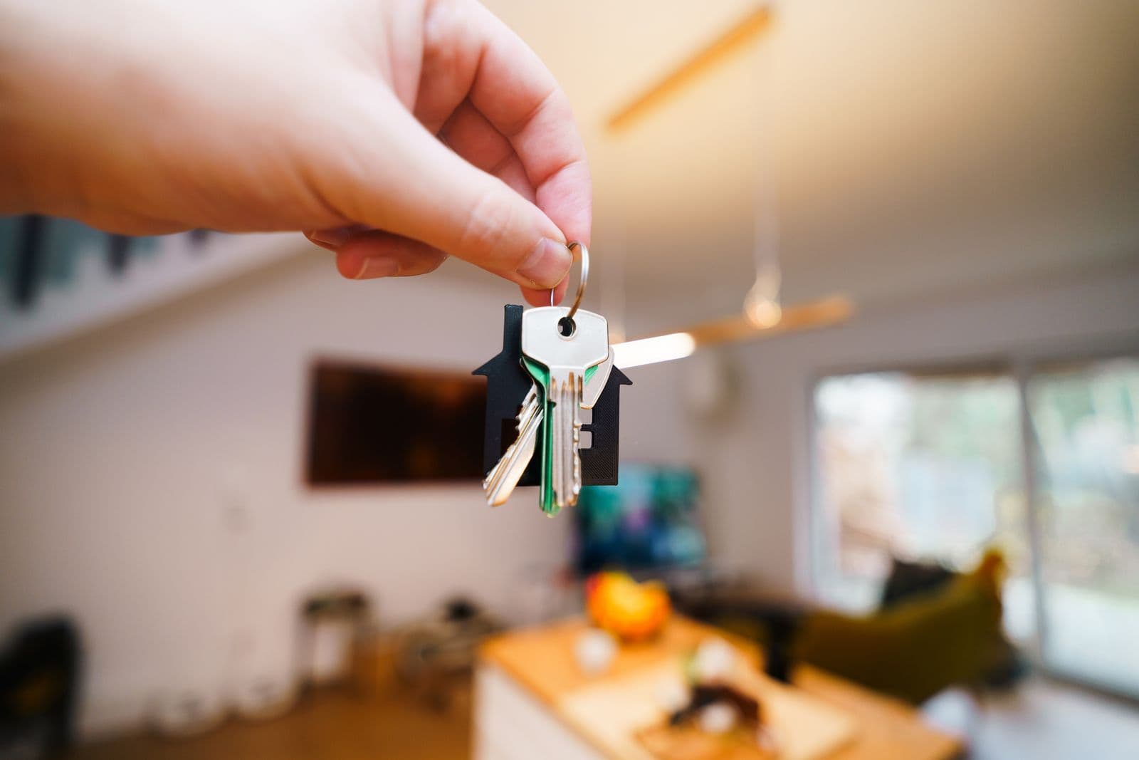 Hand holding house keys in a home interior