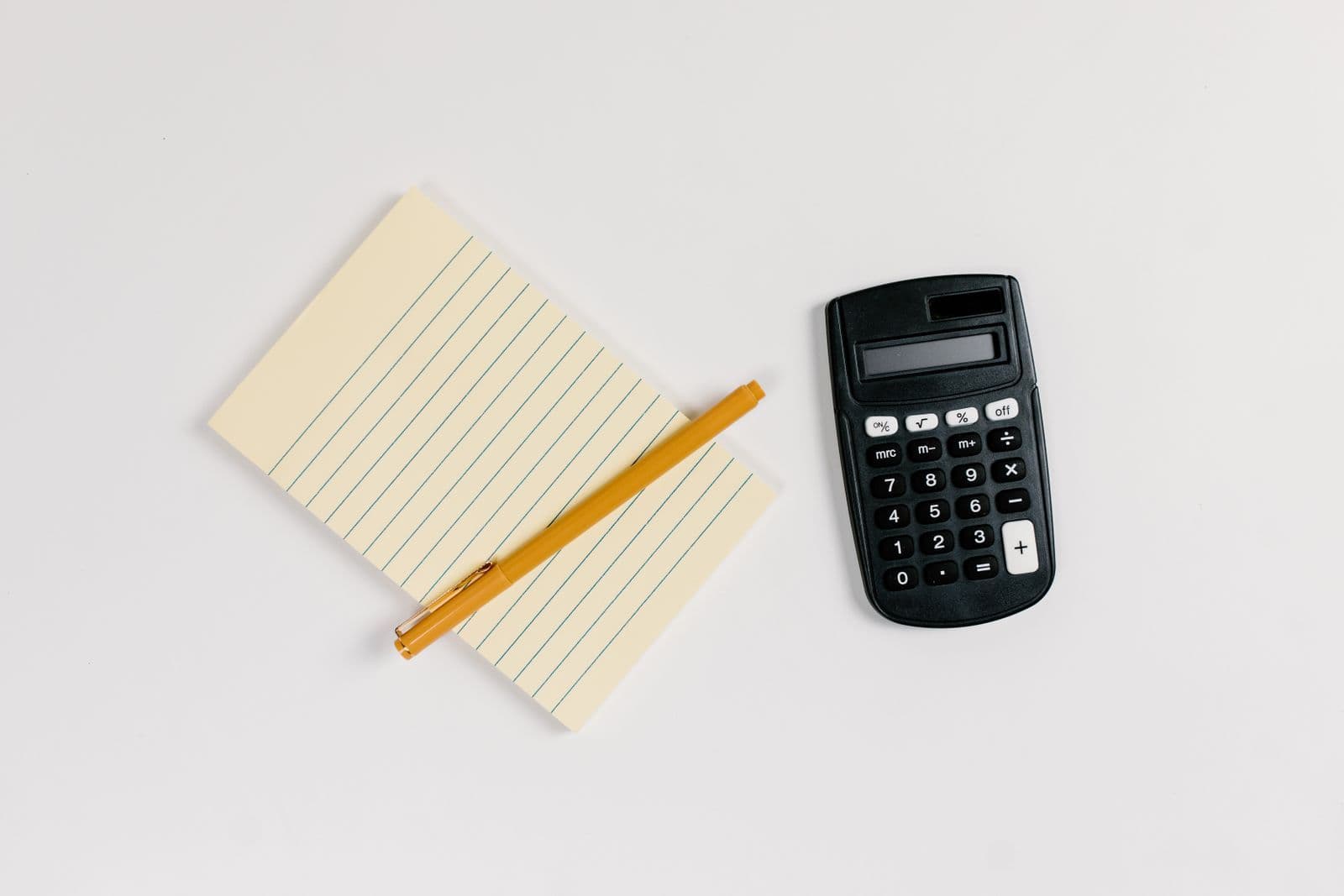 Black calculator beside a yellow notepad