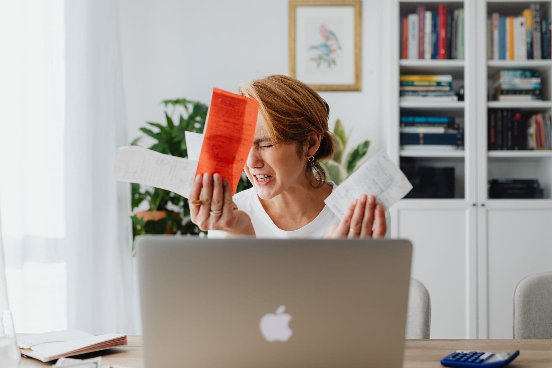 Woman feeling worried while reviewing a price-rise notice beside her laptop