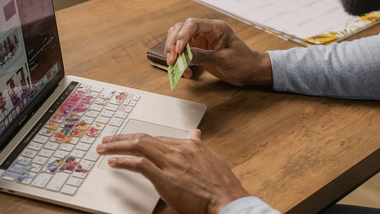 A person using a laptop with a payment card