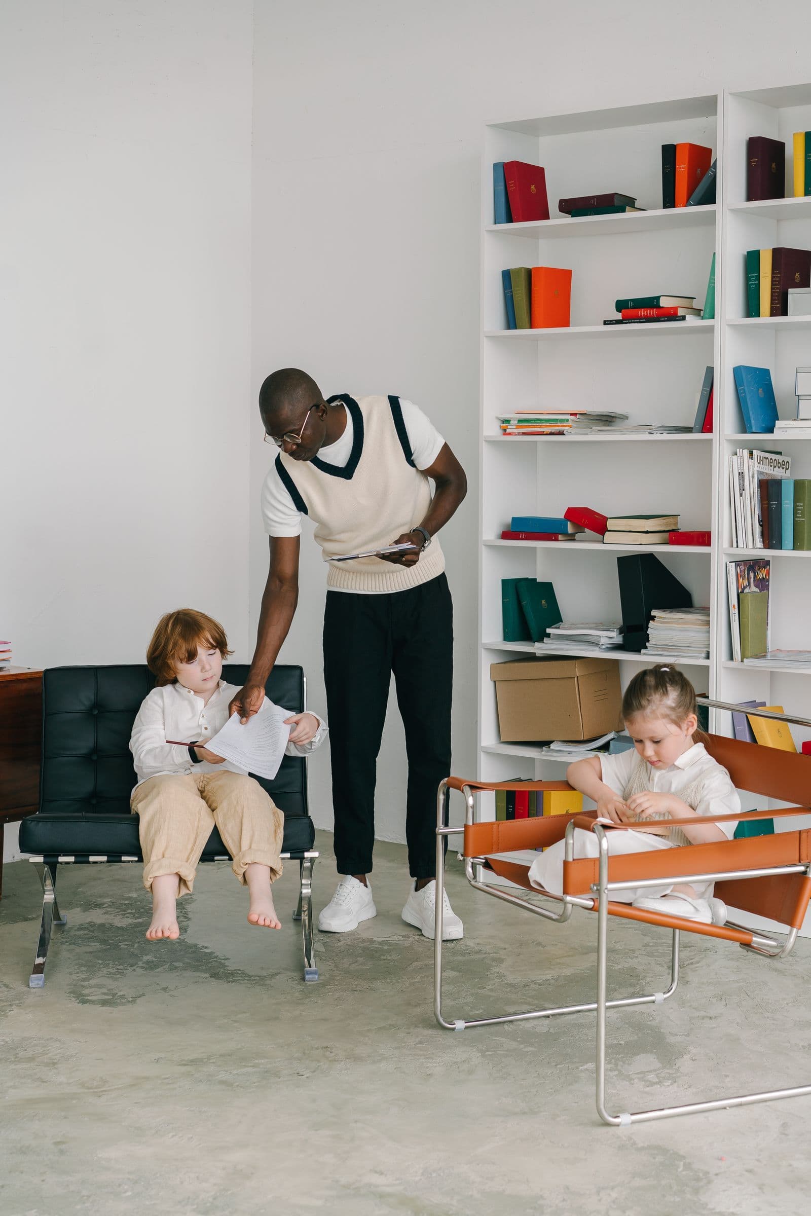 An adult helping seated children with paper activities in an office