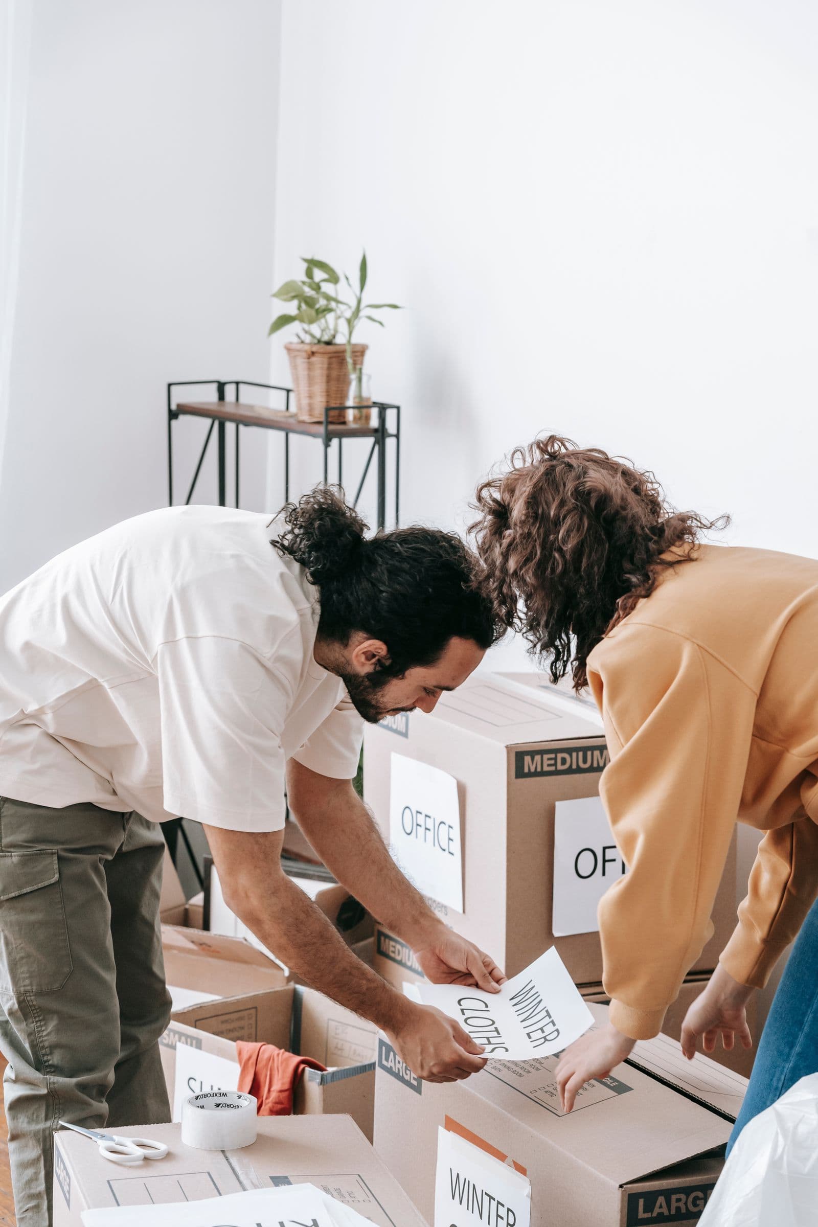 Two people organising labelled cardboard boxes for a move