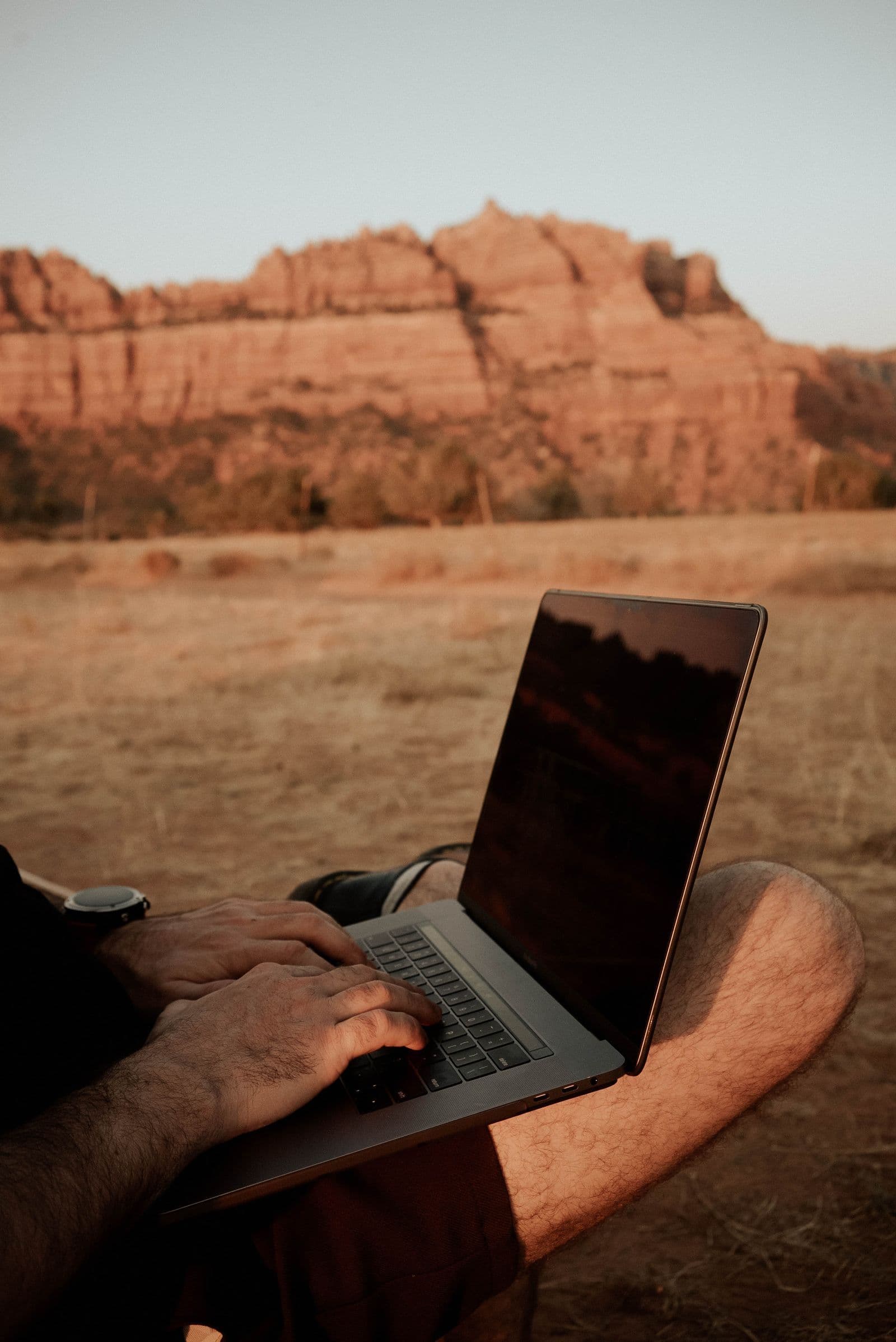 Person using a laptop outdoors in a rural landscape