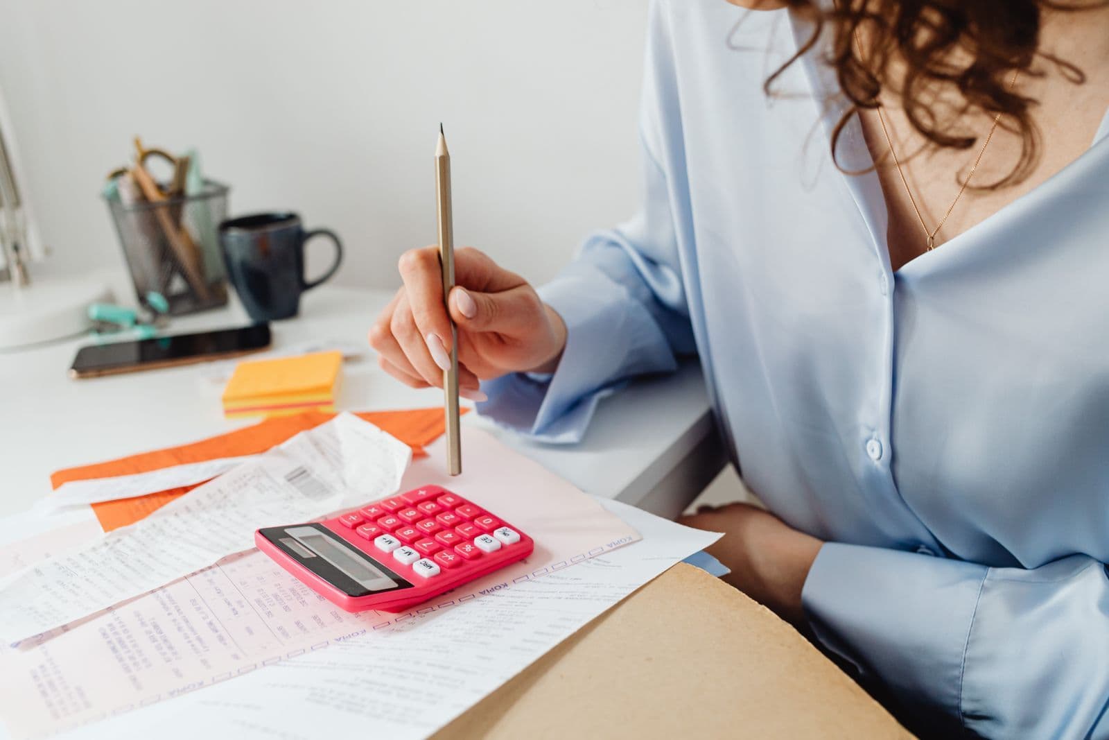 Hands using a calculator beside household paperwork