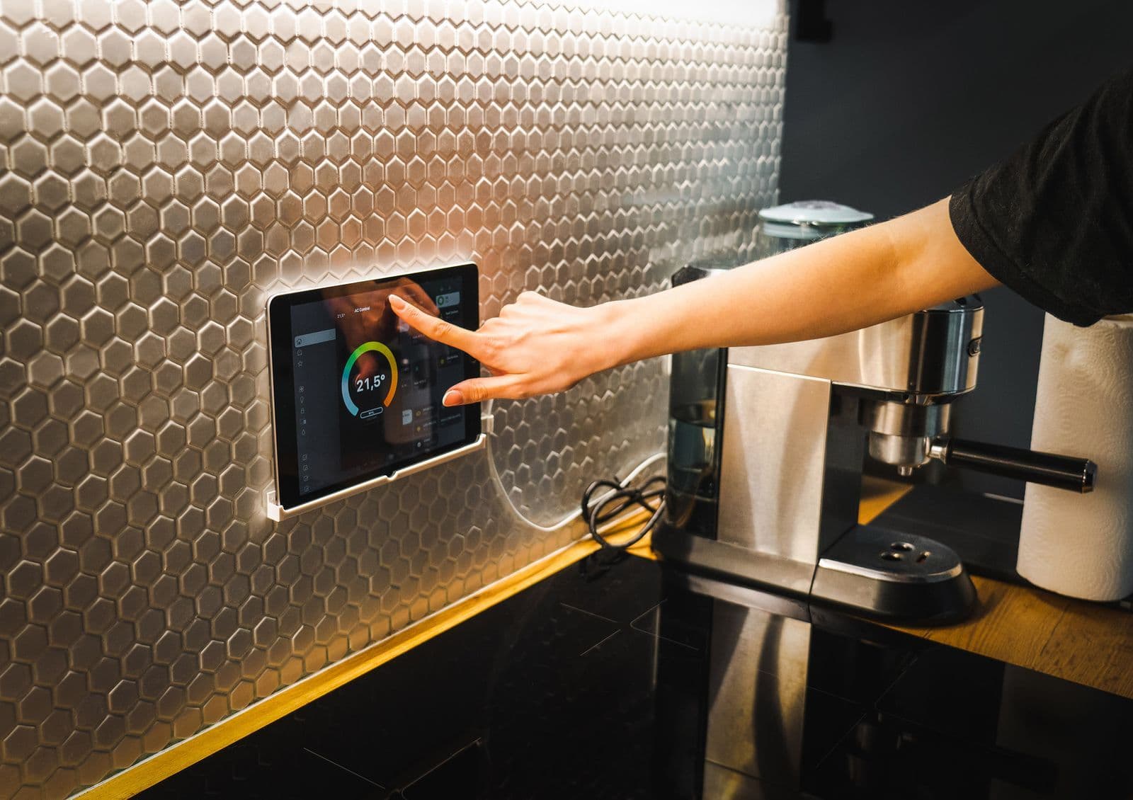 A hand using a tablet beside appliances in a home kitchen