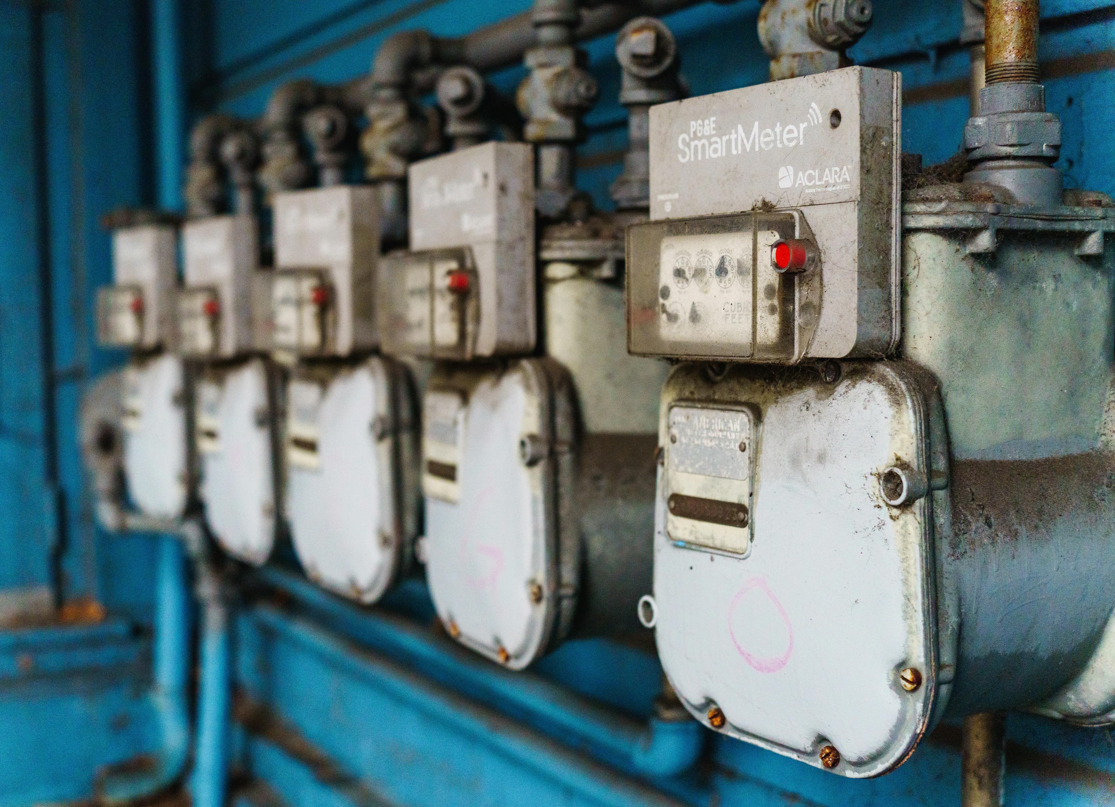Row of smart utility meters mounted on a blue wall.