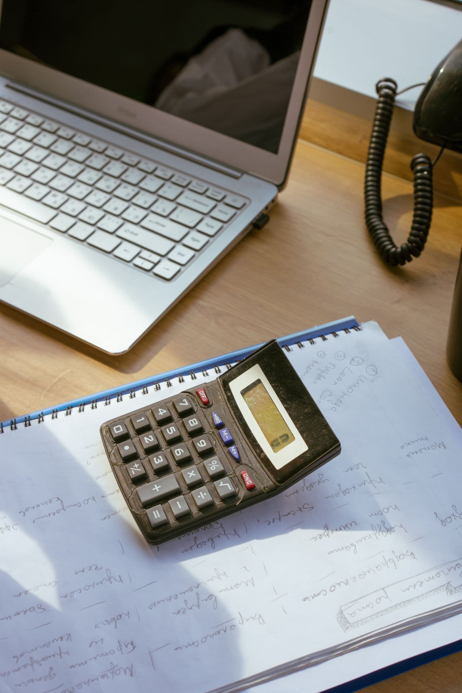 Calculator and laptop beside financial paperwork