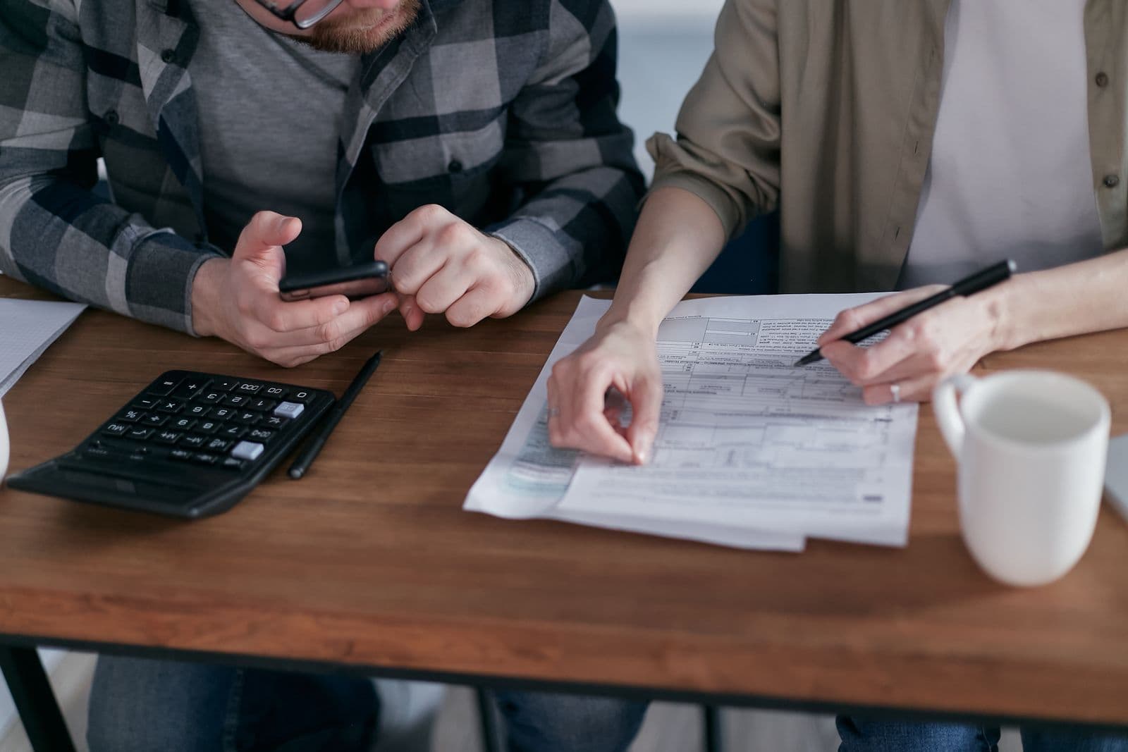 Two people checking documents and a calculator at home