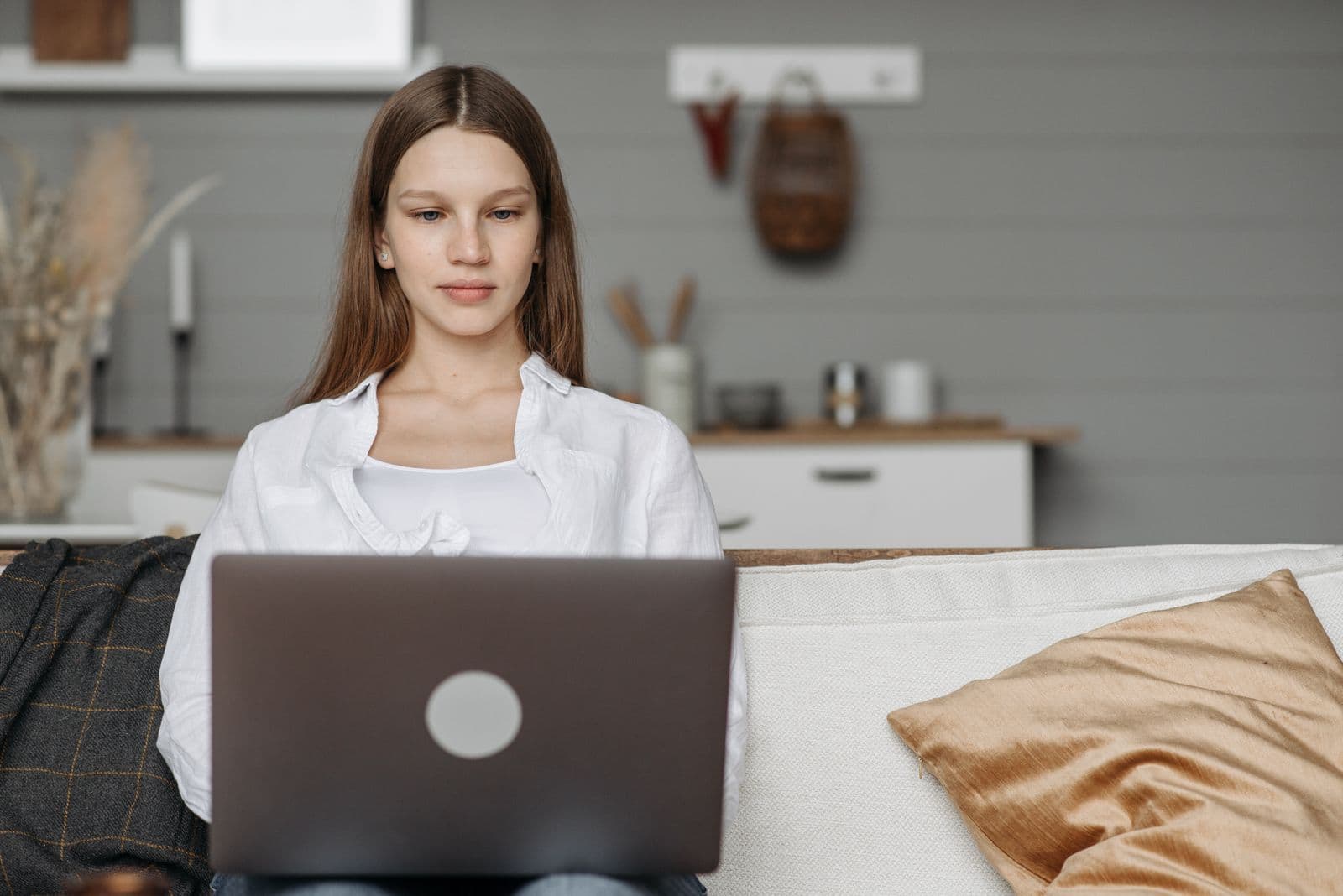 A woman using a laptop while seated on a sofa at home