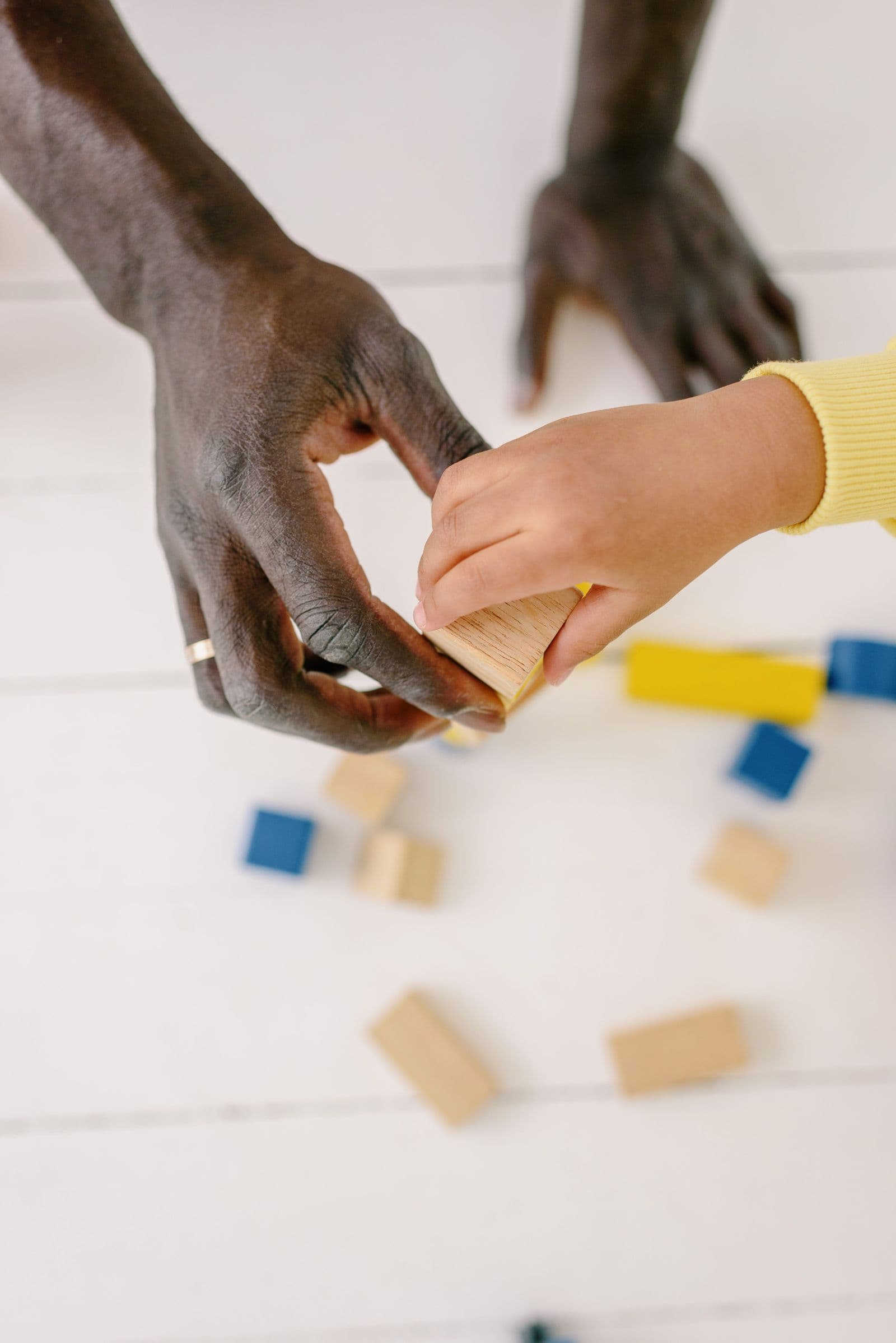 An adult and child arranging coloured wooden blocks together