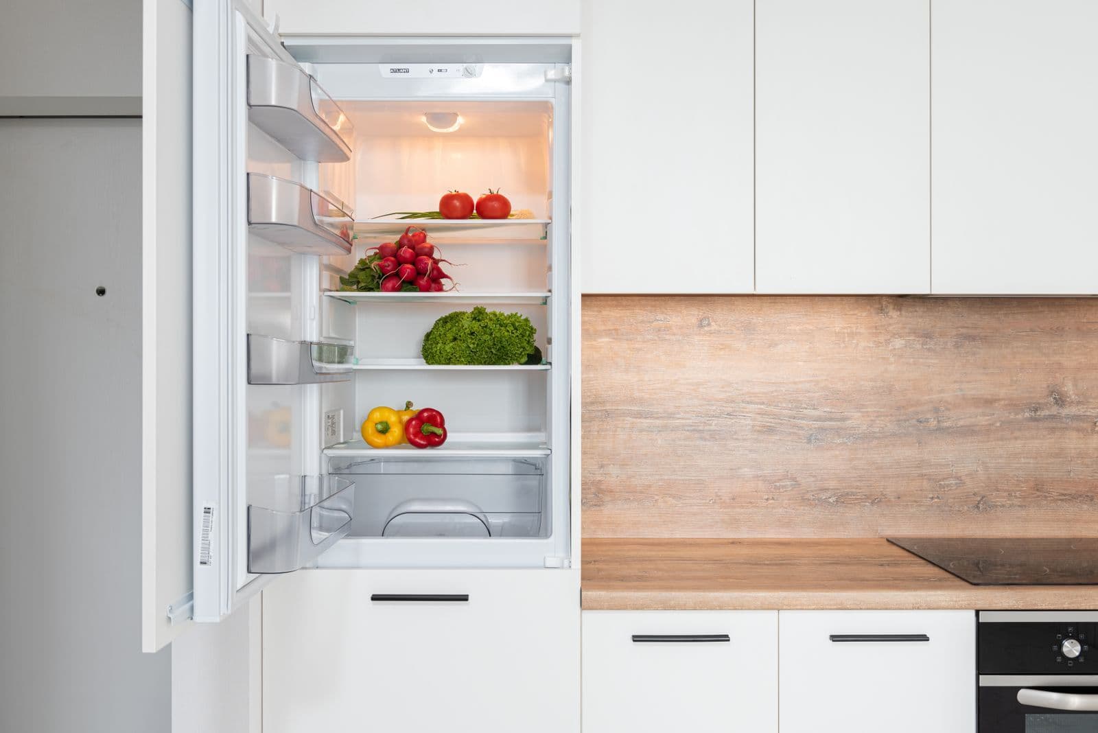 Open refrigerator with vegetables in a modern kitchen